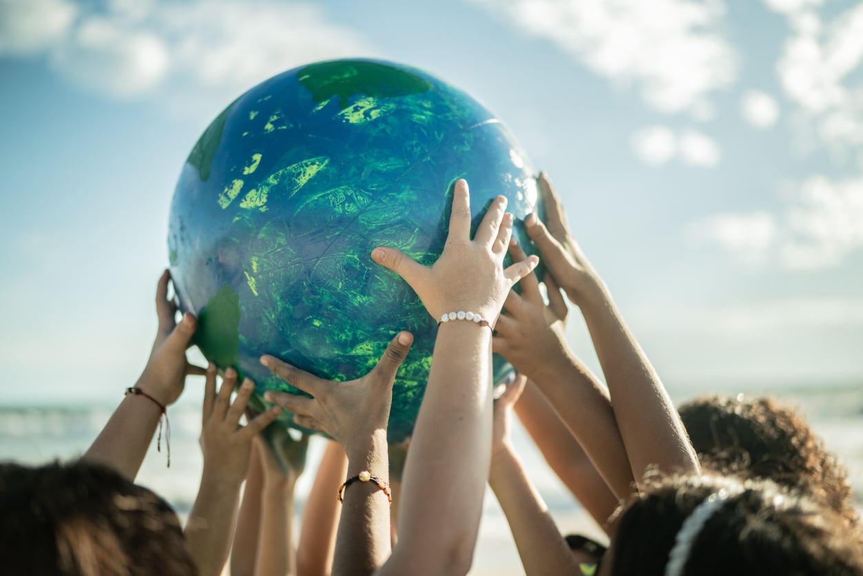 Group of people holding up a large globe.
